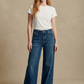 Woman wearing a white t-shirt and blue jeans against a beige background