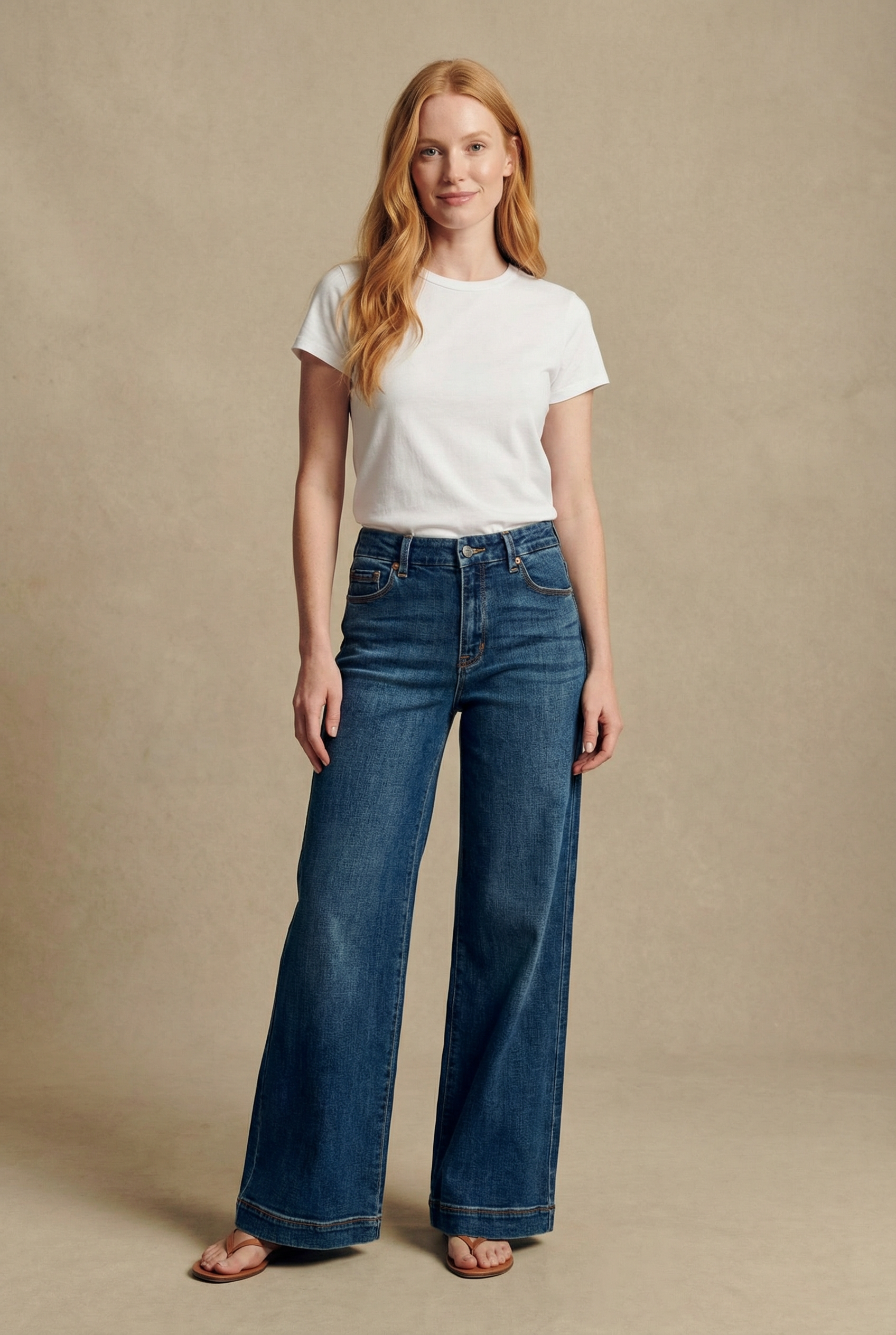 Woman wearing a white t-shirt and blue jeans against a beige background